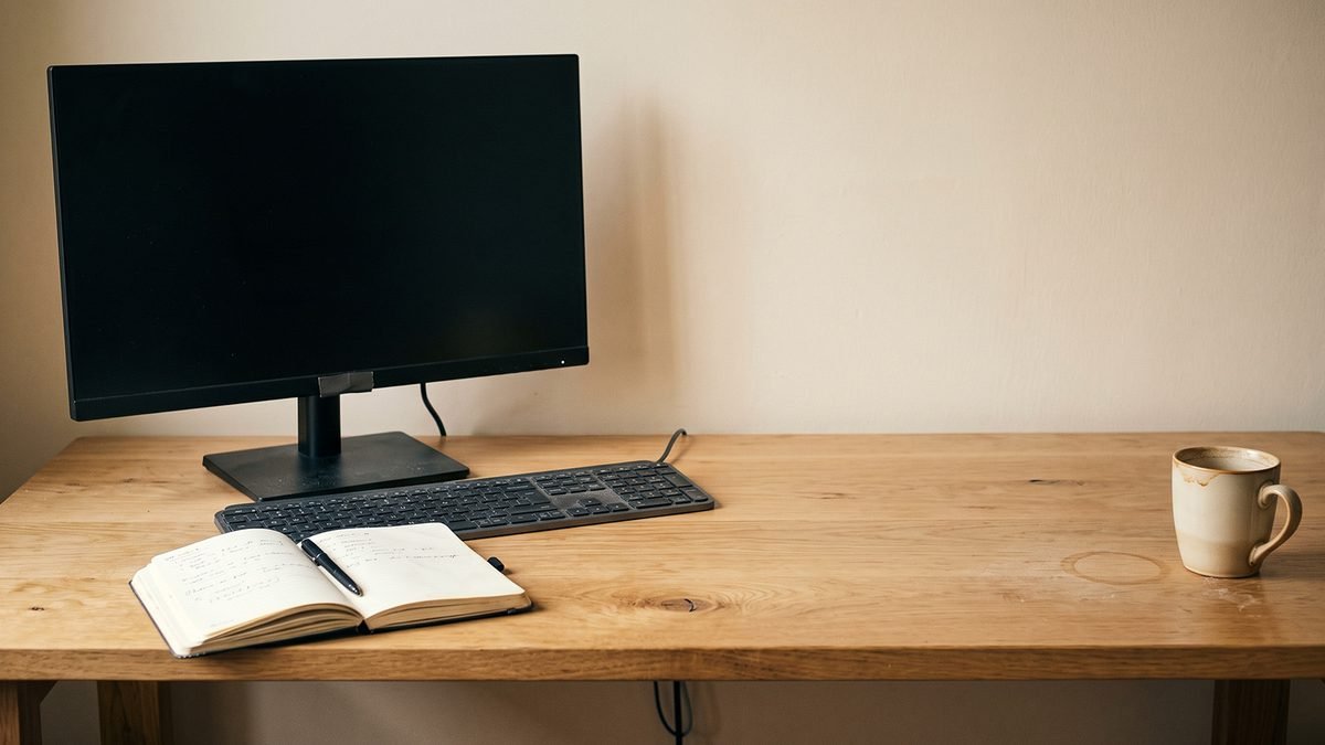 Single monitor on a bare oak desk, no other glowing objects
