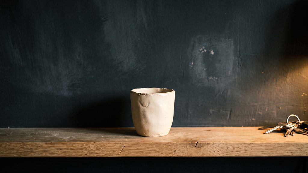 Matte charcoal surface beside cream ceramic in low warm light